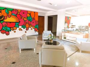 a living room with white chairs and a large painting at Hotel Riviera in Araçatuba