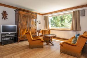 salon z telewizorem, stołem i krzesłami w obiekcie Chalet Grimm w mieście Adelboden