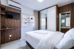 een slaapkamer met een wit bed en een flatscreen-tv bij Apto confortável a 4min do mar RTA042 in Balneário Camboriú