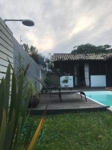 a wooden deck with a bench next to a pool at Casa Jasmim in Imbituba