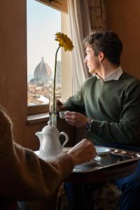 een man aan een tafel die uit een raam kijkt bij Grand Hotel Adriatico in Florence