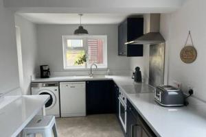 a white kitchen with a sink and a dishwasher at Collingwood House by StayStaycations in Bristol