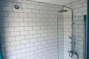 um chuveiro na casa de banho com azulejos brancos em Collingwood House by StayStaycations em Bristol