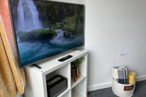 a flat screen tv sitting on a white stand at Collingwood House by StayStaycations in Bristol