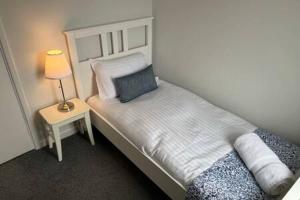 um pequeno quarto com uma cama com um candeeiro sobre uma mesa em Collingwood House by StayStaycations em Bristol