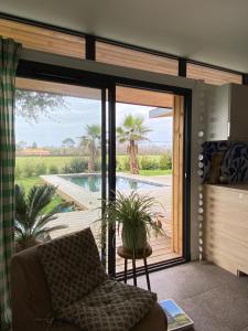 een woonkamer met een glazen schuifdeur naar een zwembad bij Calico, dépendance proche Hossegor et 15 min plage in Saubion