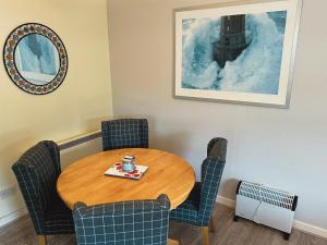 Cette chambre comprend une table, des chaises et un coffeeucer. dans l'établissement Feorline Cottage, à Lochgoilhead