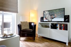 ein Wohnzimmer mit einem TV und einem Stuhl in der Unterkunft Rodehuus Wohnung 10 in Borkum