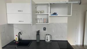 una cocina con armarios blancos y fregadero en NOVÝ krásný apartmán - 15 min od centra en Praga