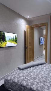 a bedroom with a bed with a television on the wall at Escalade BAYTI 2 in El Jadida