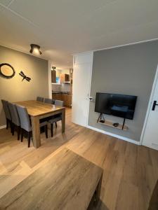 a dining room with a table and a flat screen tv at Puur Texels 9a in De Koog