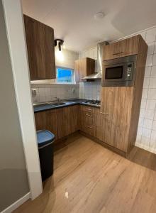 a kitchen with wooden cabinets and a microwave at Puur Texels 9a in De Koog