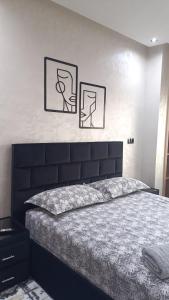 a bedroom with a large bed with two pictures on the wall at Escalade BAYTI 2 in El Jadida