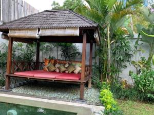a bench in a gazebo next to a pool at Zolina Villa 4 Bedrooms in Kerobokan