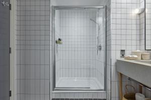 a shower in a bathroom with white tiles at One Hundred Shoreditch in London