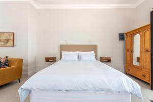 a bedroom with a large white bed and a chair at Franschhoek Colours in Franschhoek