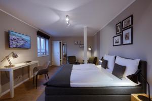 ビューズムにあるHotel Astra Marisの大きなベッドとデスクが備わるホテルルームです。