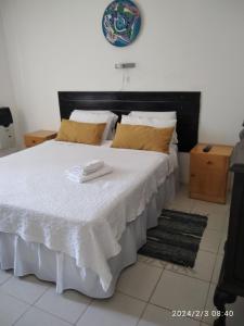 1 dormitorio con 1 cama blanca grande con almohadas amarillas en Luciana G en Río Ceballos