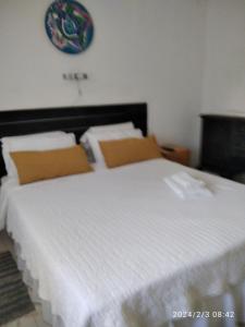 a bedroom with a bed with white sheets and a clock on the wall at Luciana G in Río Ceballos