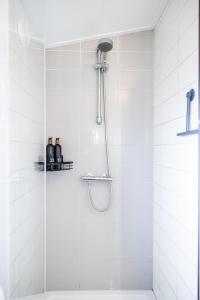 a shower in a white tiled bathroom at Leva - Logeren in Drenthe in Doldersum