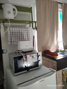 a microwave on top of a refrigerator in a kitchen at Luciana G in Río Ceballos