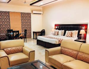 a hotel room with a bed and a couch and chairs at When In Gurgaon - ARTEMIS HOSPITAL 1 Min Walk, FORTIS & MEDANTA 4 Mins Drive in Gurgaon