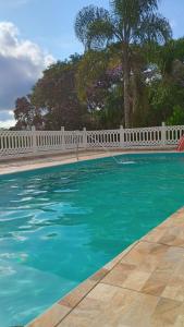 une piscine avec une clôture blanche et de l'eau bleue dans l'établissement Chácara nossa senhora Aparecida, à Suzano