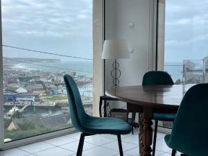 einen Tisch und Stühle in einem Zimmer mit einem großen Fenster in der Unterkunft Maison vue mer, port et ville in Fécamp