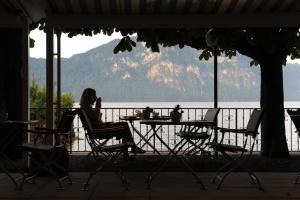 eine Frau, die an einem Tisch mit Blick auf das Wasser sitzt in der Unterkunft Seehof Hotel Du Lac in Weggis