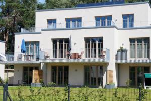 uma grande casa branca com cadeiras na varanda em Bickbeeren Schweiz Villa Catrina, App 05 em Dierhagen