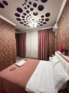 um quarto com uma cama grande e um tecto com pontos roxos em Lux em Türkistan