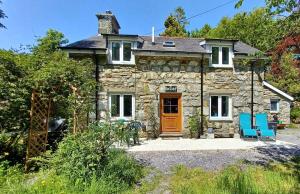 a stone house with blue chairs in front of it at Cae Tudur Remote Rural Cottage near Barmouth in Barmouth