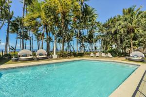 een zwembad met stoelen en palmbomen bij Alamanda Poolside Suite—Resort Living by the Beach in Palm Cove