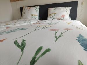 a bed with a white comforter with flowers on it at De Dagloner in Nieuwlande