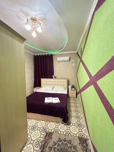 Habitación pequeña con cama y pared verde en Lux en Türkistan