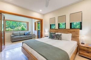 a bedroom with a large bed and a couch at Flagstaff Pavillion - A Lush Subtropical Paradise in Port Douglas