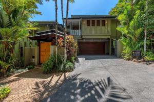 a house with a driveway and palm trees at Flagstaff Pavillion - A Lush Subtropical Paradise in Port Douglas