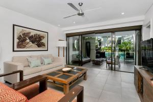 a living room with a couch and a table at Poolside Bliss: A Modern Resort Sanctuary in Port Douglas