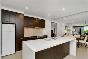 a kitchen with a white counter and a dining room at Poolside Bliss: A Modern Resort Sanctuary in Port Douglas