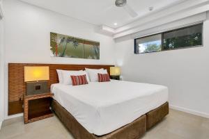 a white bedroom with a large bed and a window at Poolside Bliss: A Modern Resort Sanctuary in Port Douglas