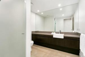 a bathroom with a sink and a toilet and a mirror at Poolside Bliss: A Modern Resort Sanctuary in Port Douglas +10 photos