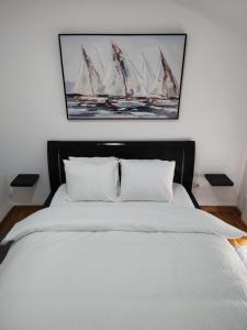 1 dormitorio con 1 cama y una pintura de veleros en Apartman Visnjica, en Rospi Ćuprija