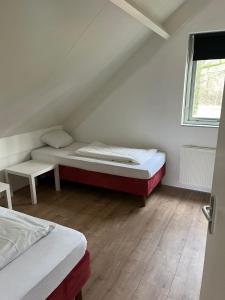 Habitación pequeña con 2 camas y ventana en Villa vakantiehuis, en Ewijk