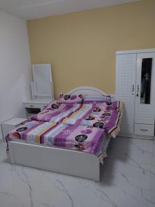 a bedroom with a bed with a purple blanket on it at Urban Lifestyle in Dubai