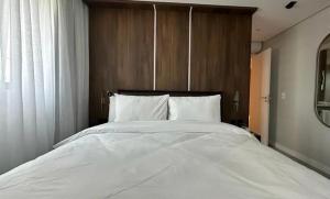 a large white bed with a wooden headboard in a bedroom at Apartamento Duplo Luxo com Jacuzi 6 lugares in Itajaí