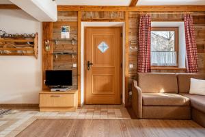 a living room with a couch and a tv and a door at Thomasegg Hof Linde in Sarntal