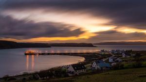a sunset over a town with a dock in the water at Skyefall Self Catering in Uig