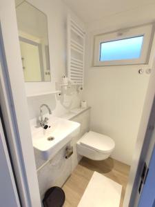 a white bathroom with a sink and a toilet at Atlanta. Een buitengewone ervaring. Dicht bij AMS. in Vinkeveen