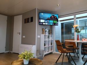 a living room with a table and a tv on the wall at Atlanta. Een buitengewone ervaring. Dicht bij AMS. in Vinkeveen