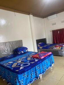 - une chambre avec 2 lits avec des draps bleus et violets dans l'établissement PENGINAPAN 77, à Pulupanda